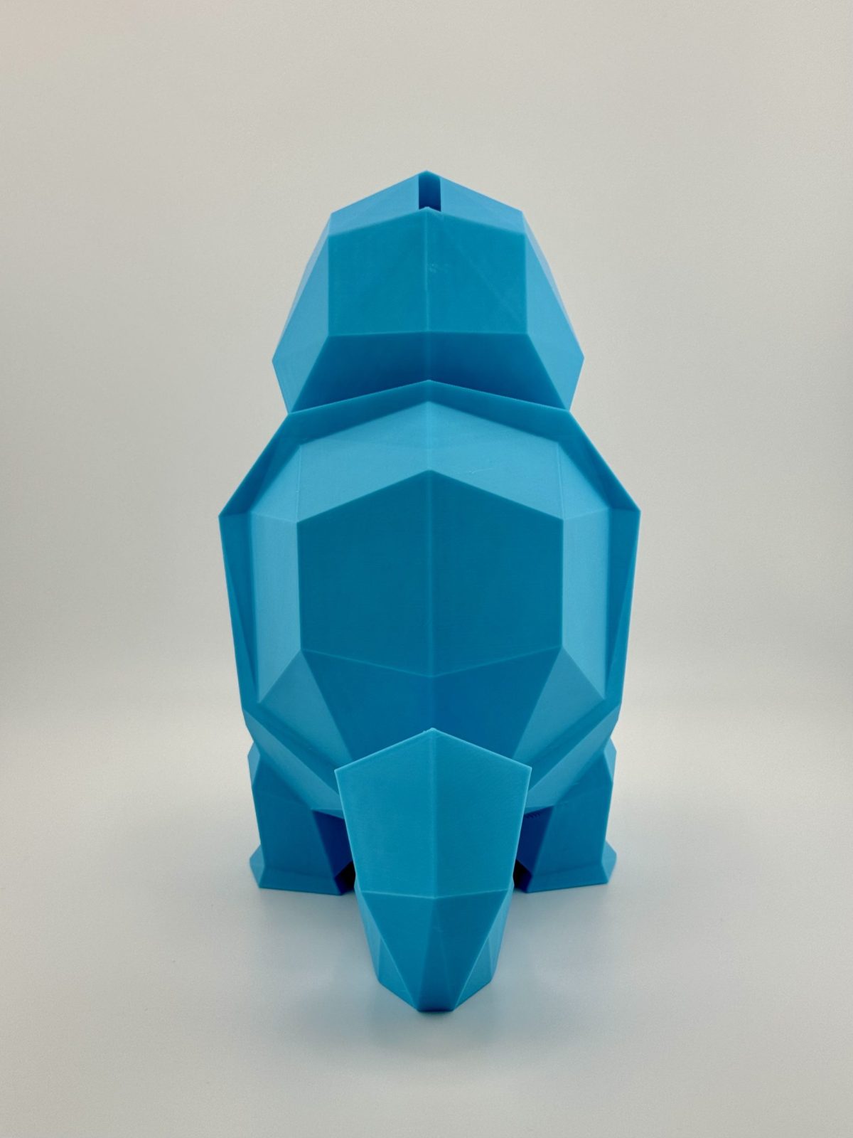 Light blue low-poly 3D-printed Squirtle coin bank, standing 19.5 cm tall with a coin slot, inspired by the classic water-type Pokémon.