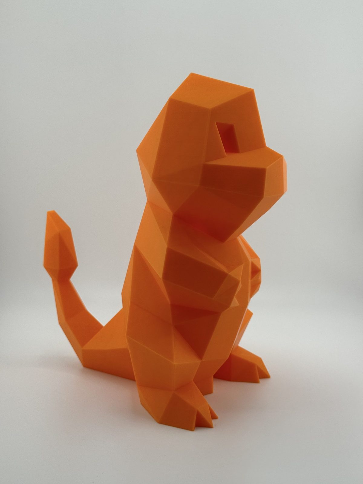 Fiery orange low-poly 3D-printed Charmander coin bank, 22.5 cm tall with a coin slot, designed to resemble the beloved Pokémon.