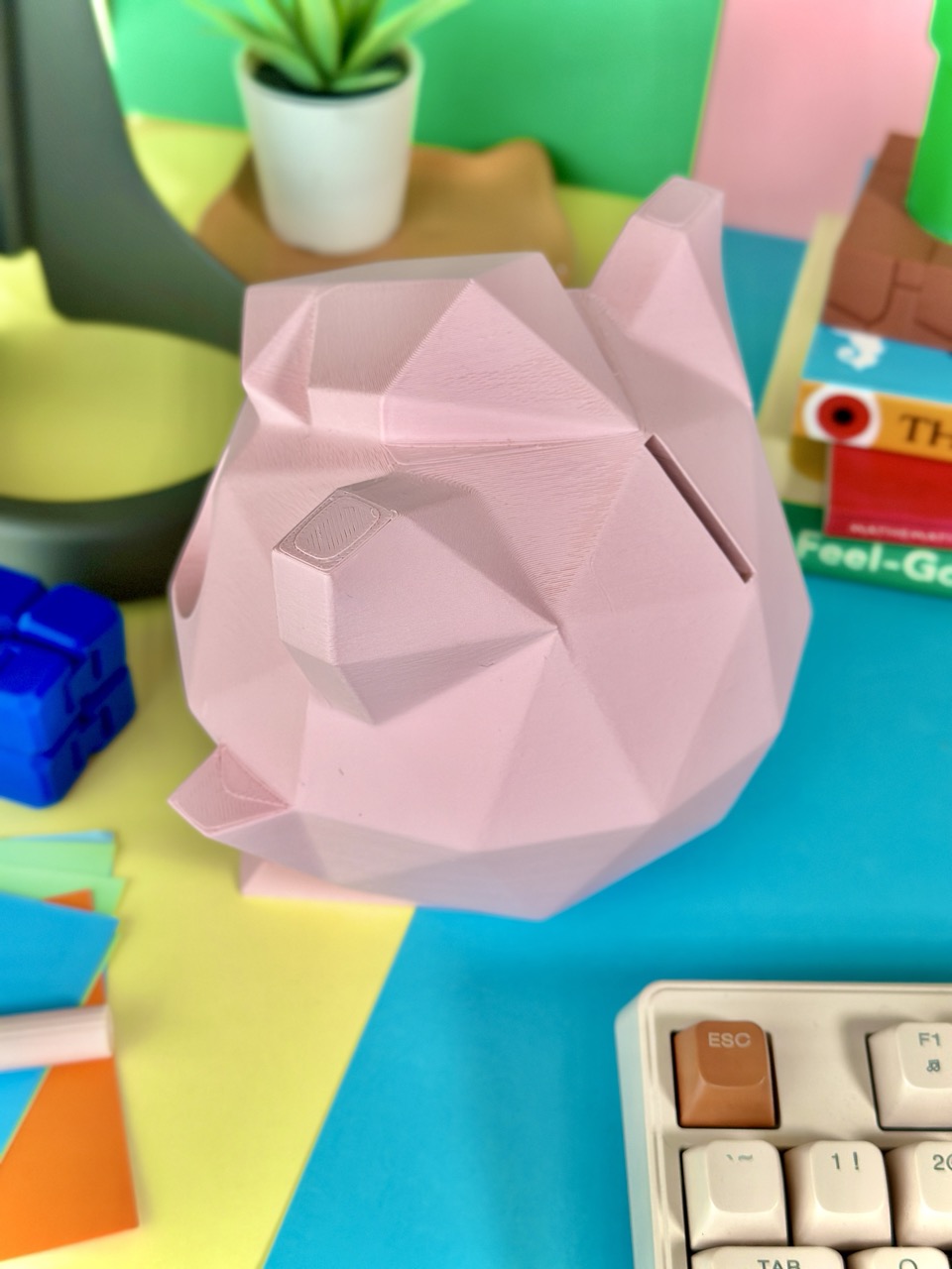 Matte light pink low-poly 3D-printed Jigglypuff coin bank, standing 15 cm tall with a coin slot, perfect for fans of the singing Pokémon.