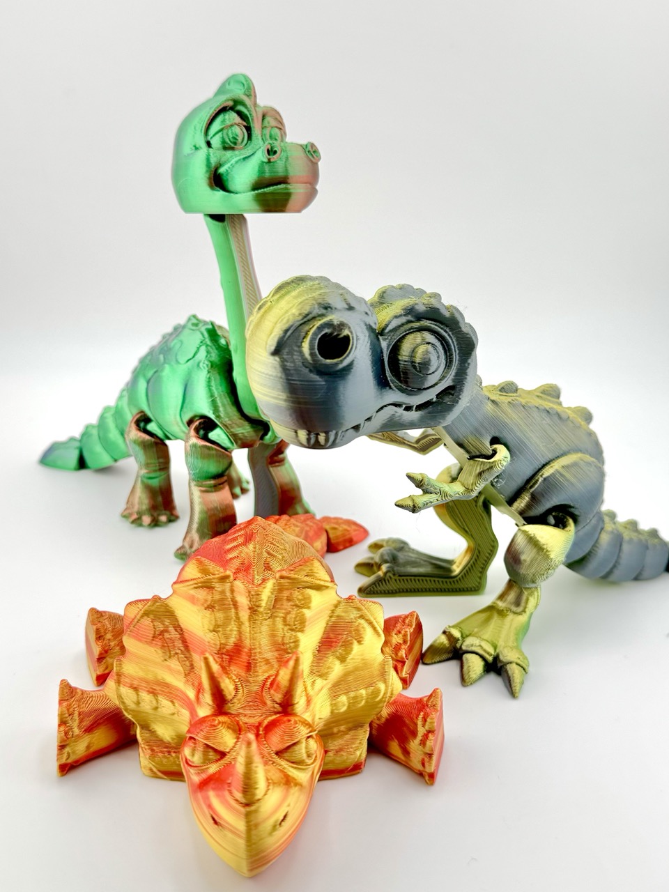 3D Printed Articulated Dino Set featuring T-Rex, Triceratops, and Brachiosaurus with detailed designs and fully articulated joints for realistic movement.